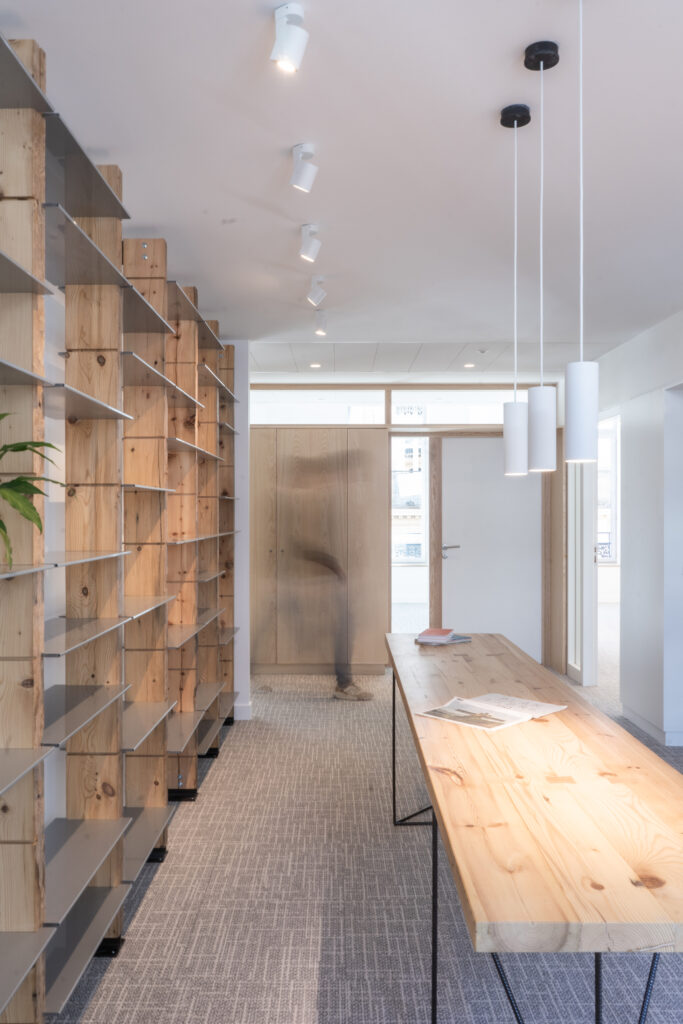 Espace de convivialité avec bibliothèque et mobilier en bois, lumière naturelle pour une ambiance chaleureuse au siège de l'Ordre des Architectes à Toulouse