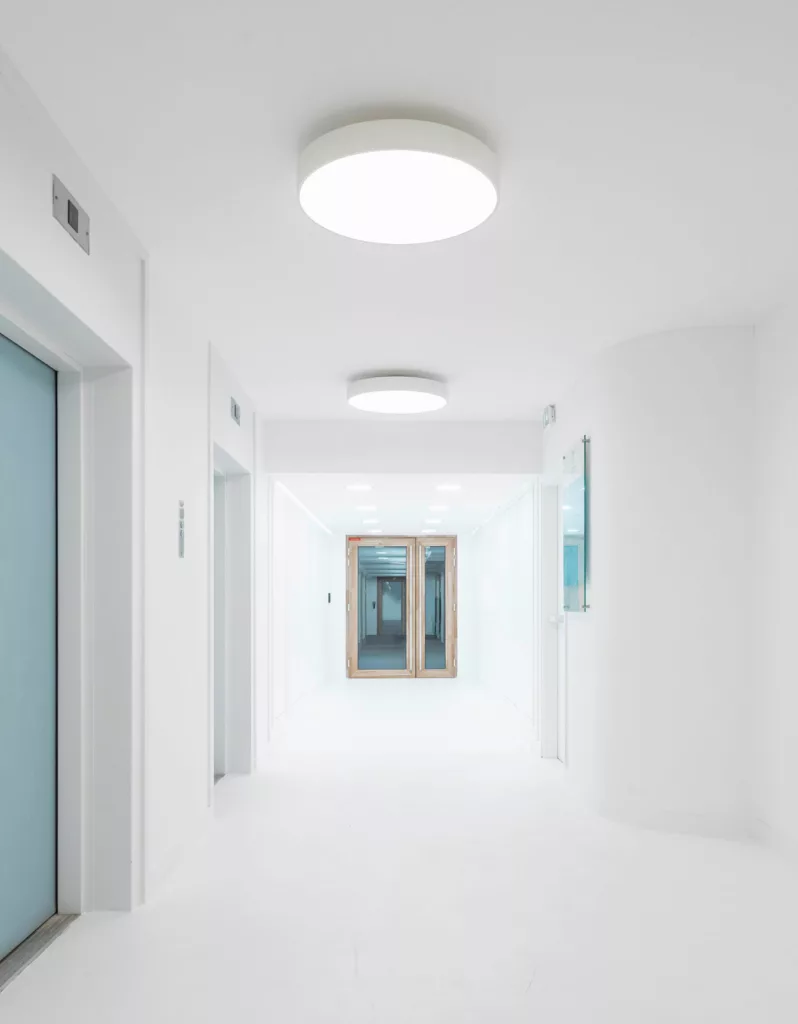 Palier et couloir d'accès au biocluster, incubateur d'entreprises biomédicales à Fontenay-aux-Roses, avec design épuré inspiré des laboratoires.